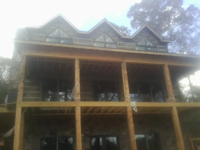 Dormers and porch framing on a large log home under construction — Roof Coating work by our crew in Imbler