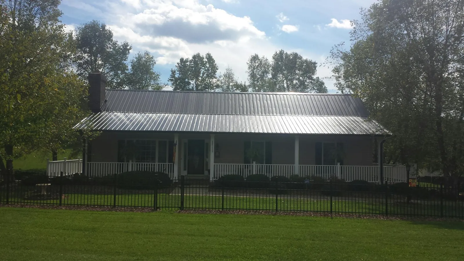 Gray metal roof on a brick ranch with a full width front porch — Gutter Guard Installation work by our crew in Imbler