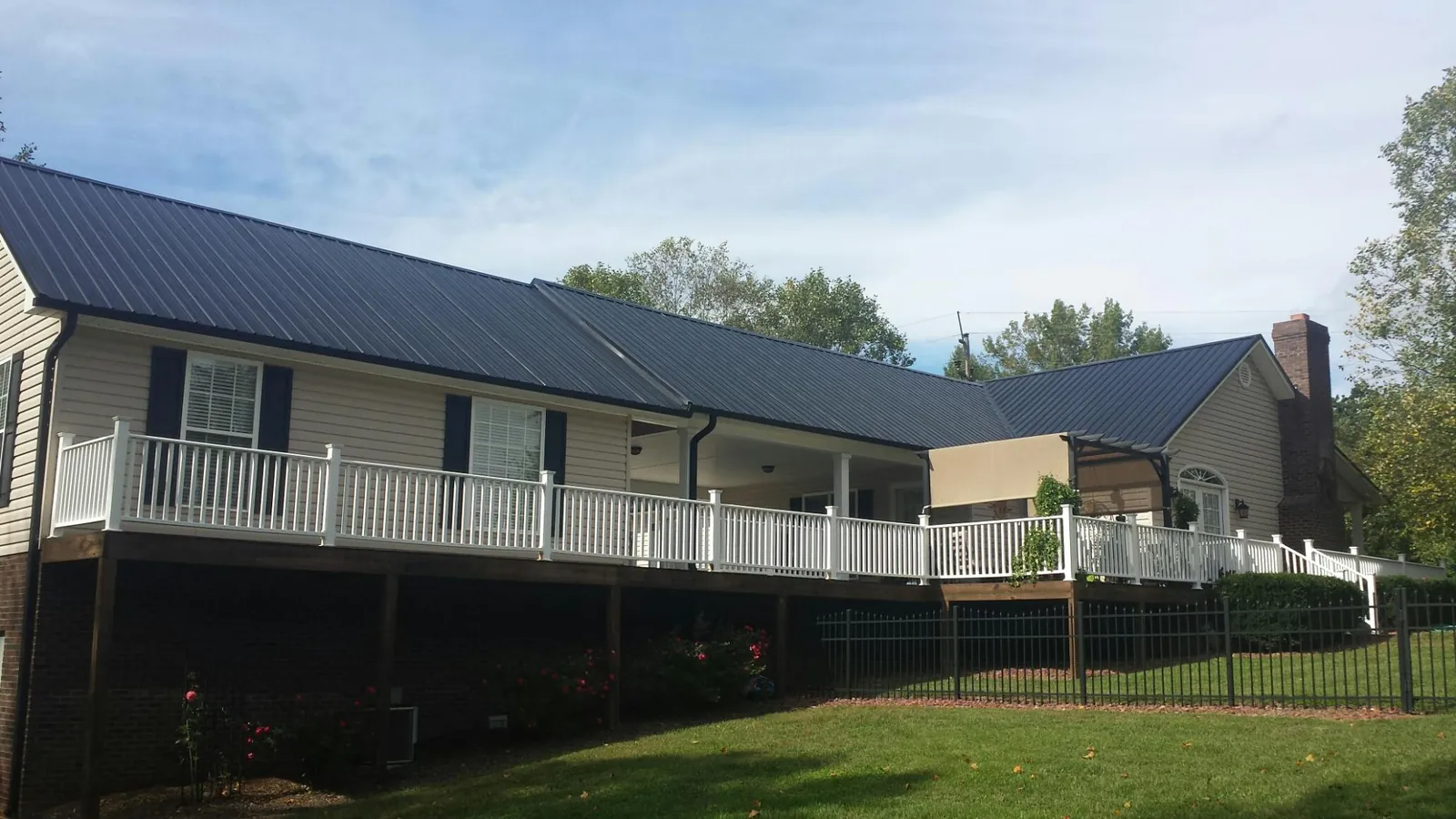 Black metal roof above a long white railed deck on a hillside home in Imbler