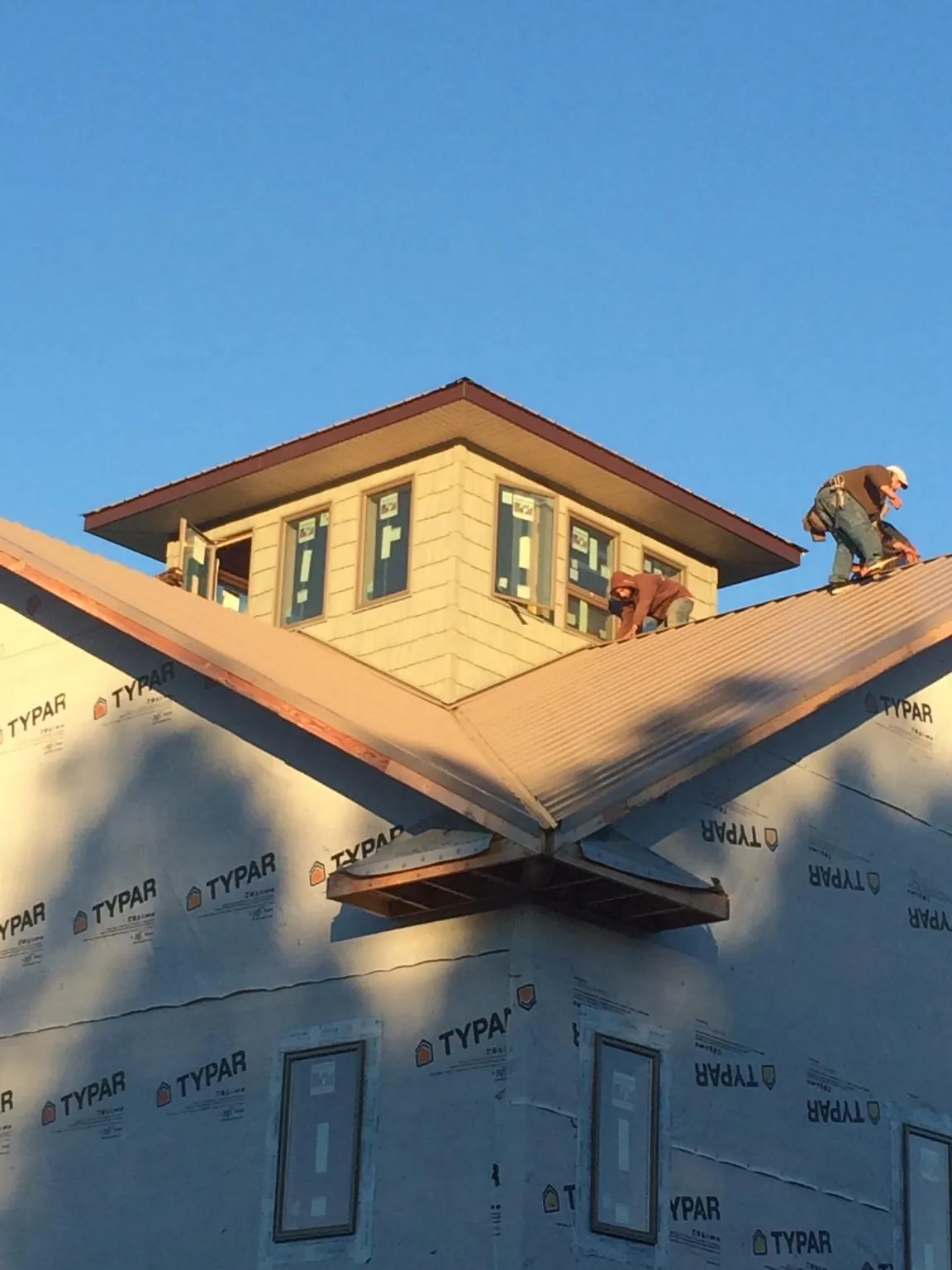 Roofers working around a rooftop cupola on a new metal roof at sunset — Roof Waterproofing in Imbler by Roofing Brothers